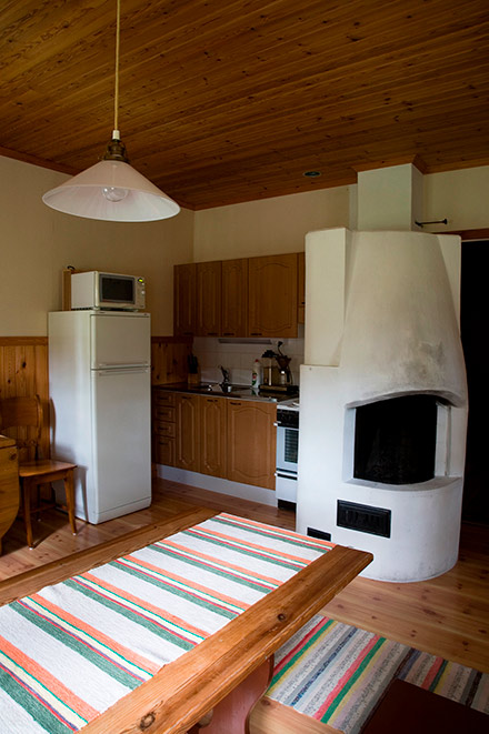 Saunatuvan keittiö, jossa valkoinen takka ja ruokapöytä