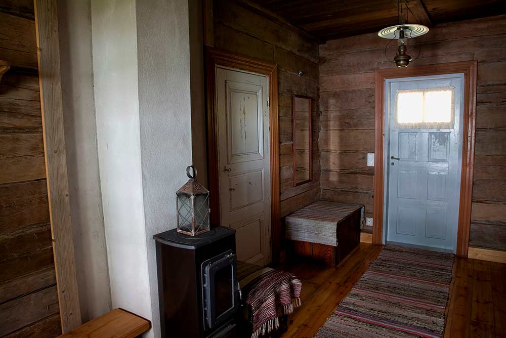 Savusaunan käytävä, jossa räsymatto, penkki ja lyhty