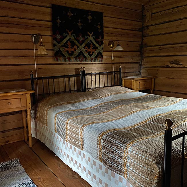 Hirsiaitan parivuode ja yöpöydät ja seinäryijy